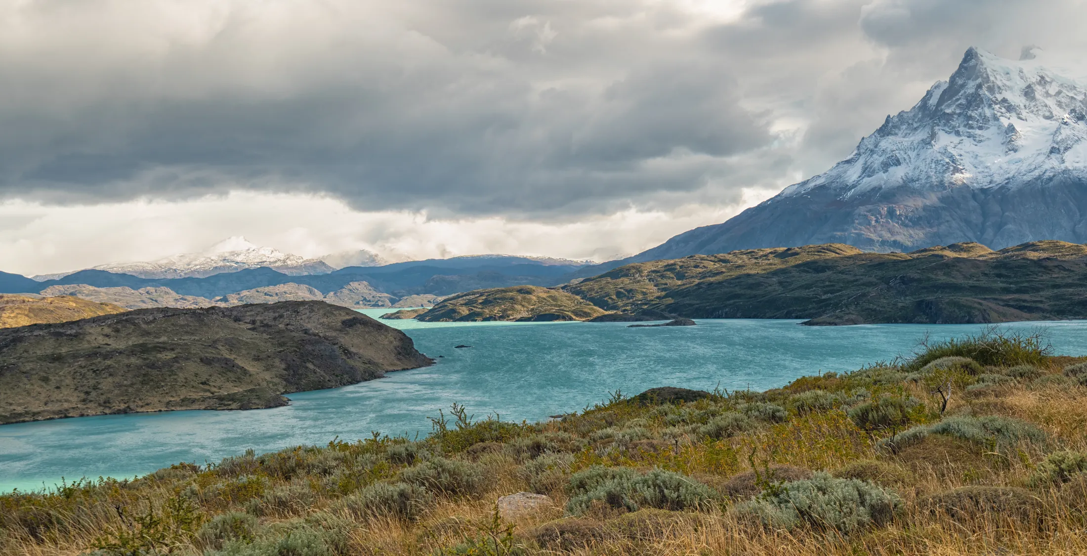 Patagonia argentina — lago turquesa y montañas nevadas bajo cielo nublado